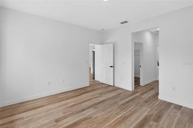 a view of an empty room with wooden floor and closet
