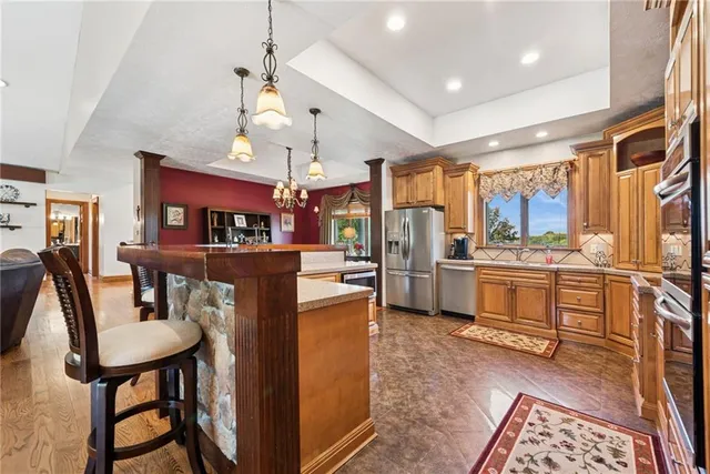 a kitchen with stainless steel appliances kitchen island granite countertop a table chairs and a refrigerator
