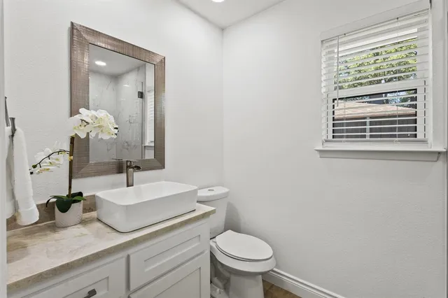 a bathroom with a granite countertop sink mirror and toilet