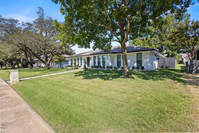 a view of a house with backyard and trees