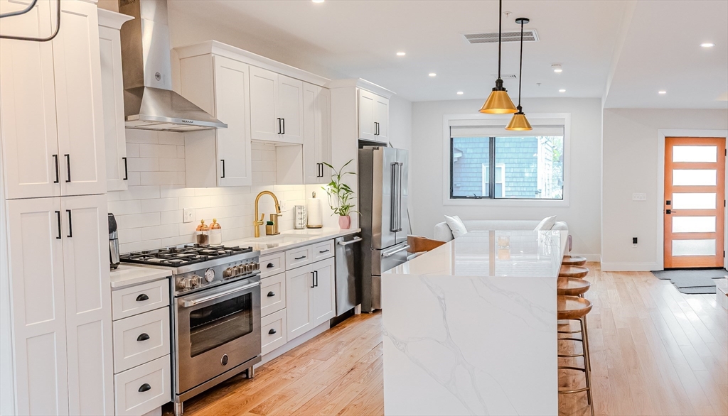 1-7 Wilcutt Road, Unit 5 Boston, MA 02121 - Photo 5 of 24 a kitchen with stainless steel appliances granite countertop a stove a sink dishwasher and a refrigerator with wooden floor