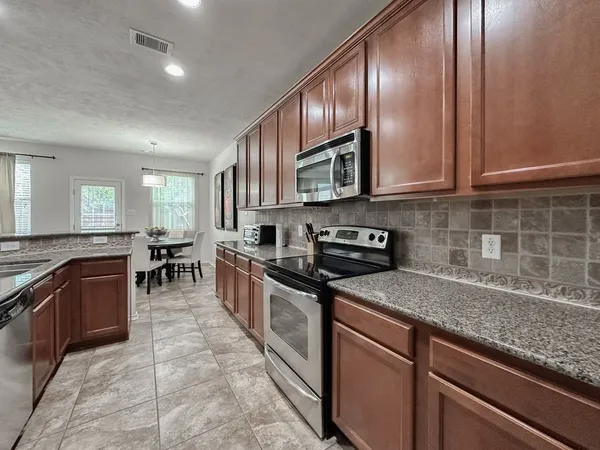 a kitchen with stainless steel appliances granite countertop wooden cabinets a stove top oven a sink and dishwasher