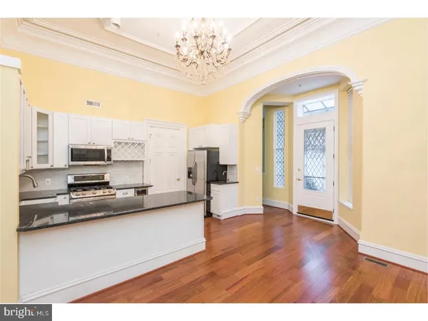 a view of a kitchen with kitchen island granite countertop wooden floor and stainless steel appliances