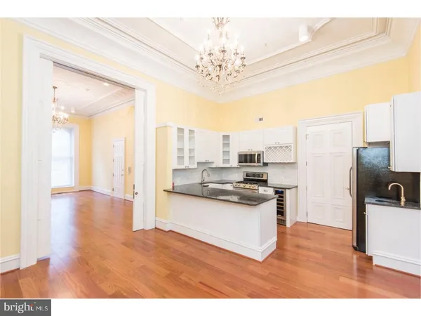 a kitchen with stainless steel appliances granite countertop a refrigerator a stove a sink dishwasher and white cabinets with wooden floor