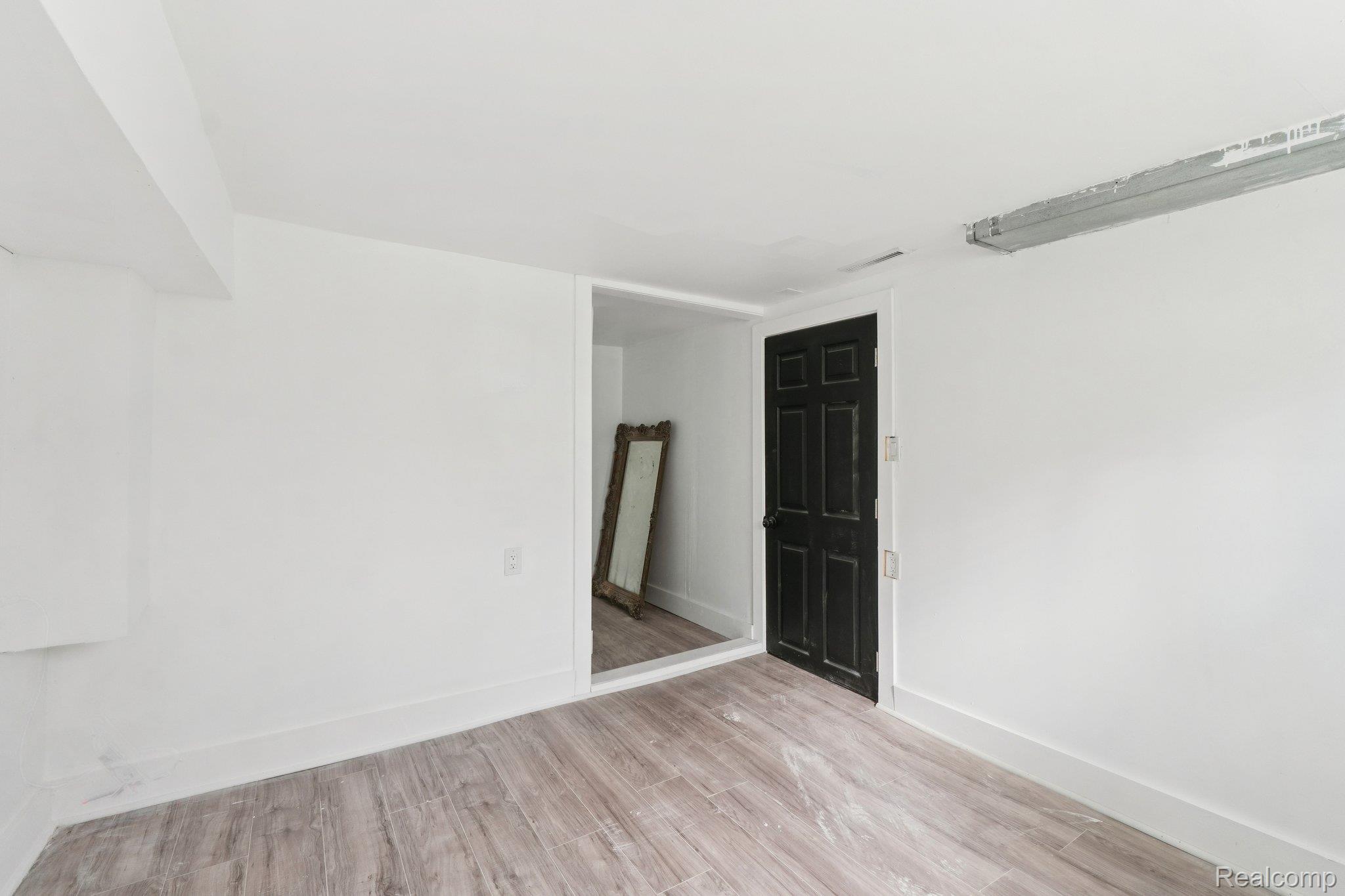 16210 Inverness Street Detroit, MI 48221 - Photo 28 of 29 Light-toned wood-finish flooring, white walls, and a paneled door with dark hardware