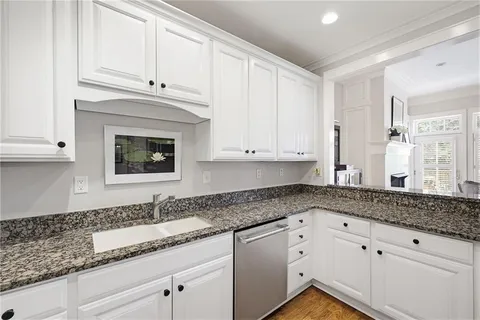 a kitchen with granite countertop white cabinets and a sink