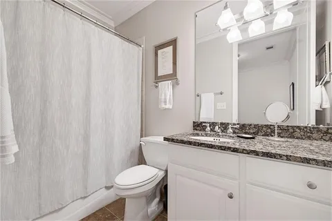 a bathroom with a granite countertop sink mirror vanity and toilet