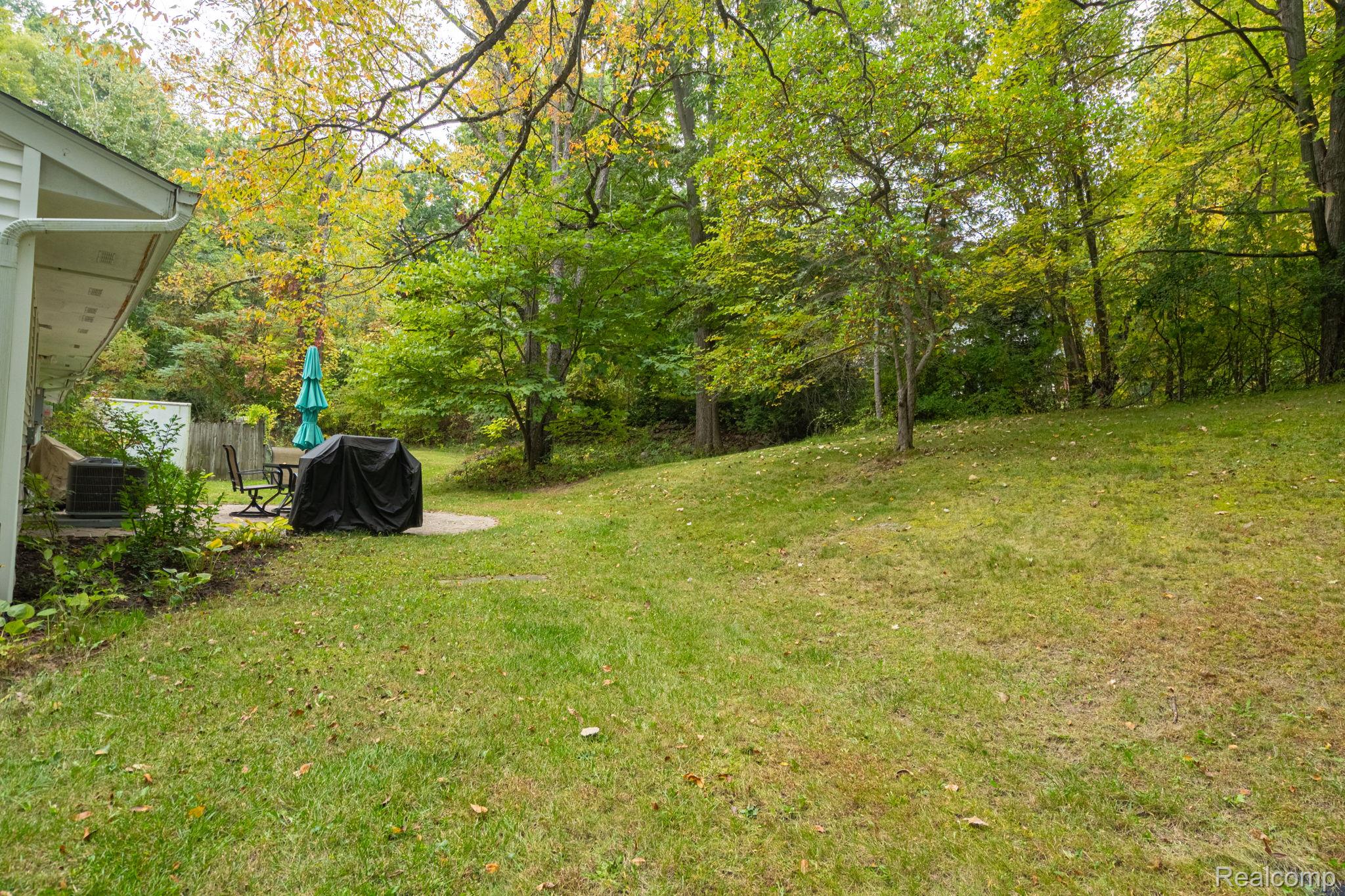 1775 Porter Road White Lake, MI 48383 - Photo 13 of 33 Expansive grassy lawn with mature trees and a concrete patio