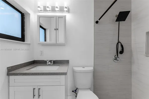 a bathroom with a granite countertop sink toilet and mirror