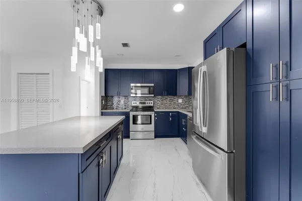 a kitchen with stainless steel appliances granite countertop a refrigerator a sink and a stove