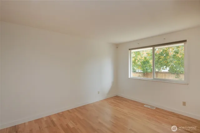 a view of an empty room with wooden floor and closet