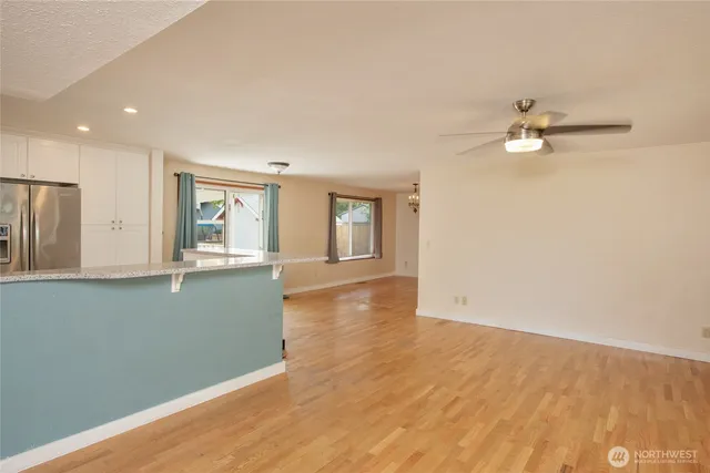 a view of empty room with wooden floor and fan