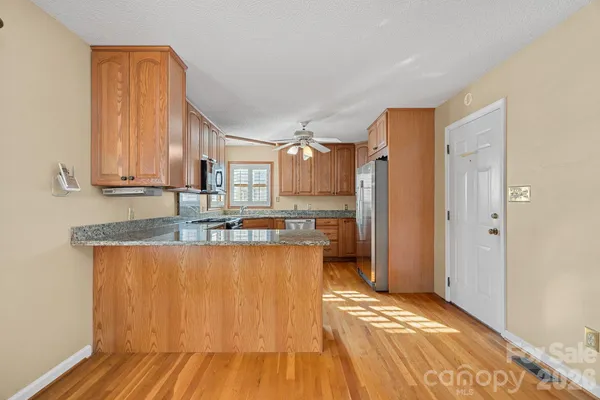 a view of a kitchen with kitchen island granite countertop wooden floor and stainless steel appliances