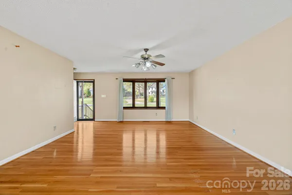 a view of an empty room with window and wooden floor