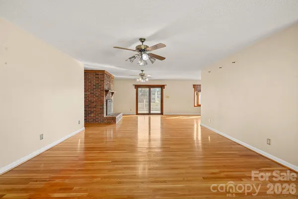 a view of an empty room with window and wooden floor