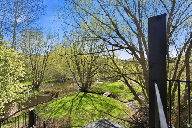 7935 Mustang Loop Road Park City, UT 84098 - Photo 53 of 60 Expansive backyard featuring a lush lawn, mature trees, a natural water feature, and a privacy fence