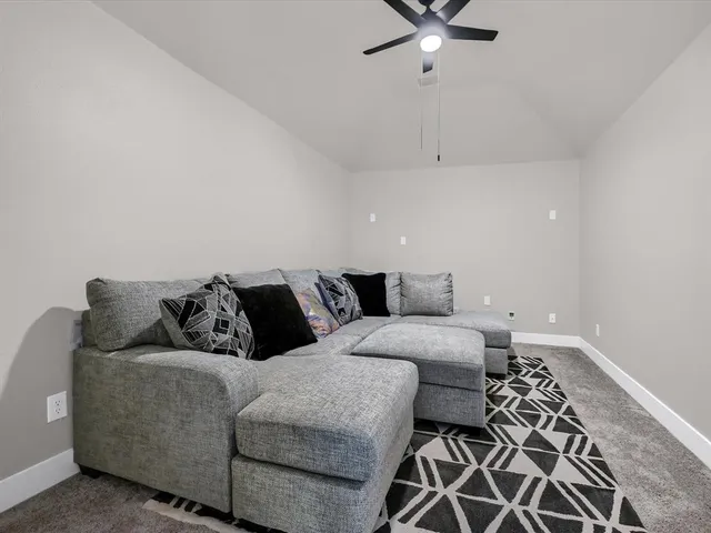 a living room with furniture and a ceiling fan