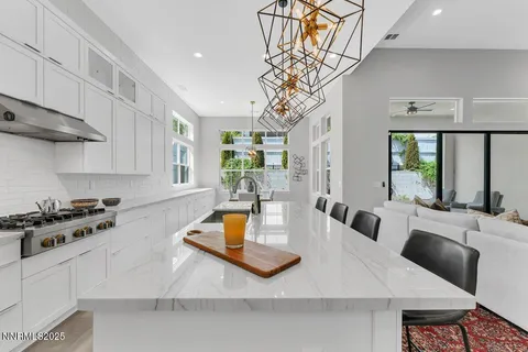 a kitchen with stainless steel appliances granite countertop a stove a refrigerator a sink a dining table and chairs with wooden floor