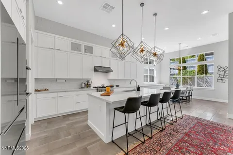 a kitchen with stainless steel appliances granite countertop a stove a sink a dining table and chairs with wooden floor