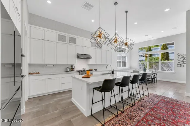 a kitchen with stainless steel appliances granite countertop a stove a sink a dining table and chairs with wooden floor