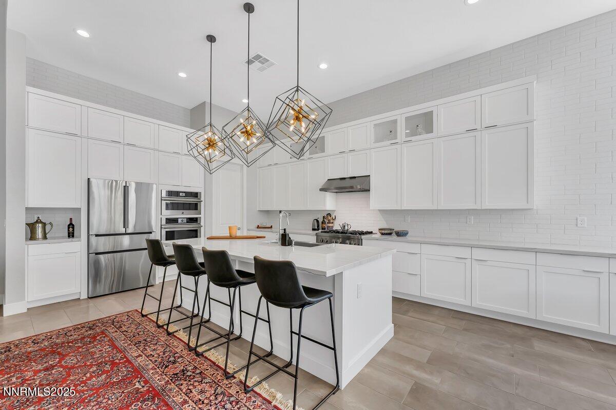 6119 South Pleasant Oak Trail Reno, NV 89511 - Photo 9 of 44 a kitchen with stainless steel appliances granite countertop a sink a stove a refrigerator cabinets and chairs