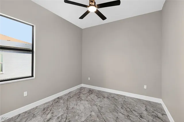 an empty room with windows and ceiling fan