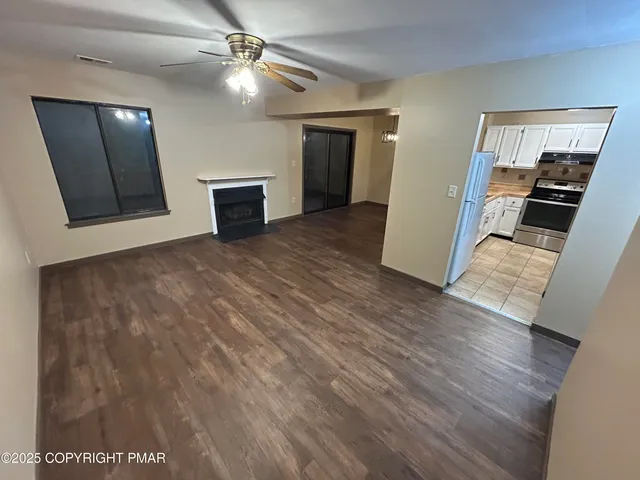 a view of a livingroom with wooden floor and a ceiling fan