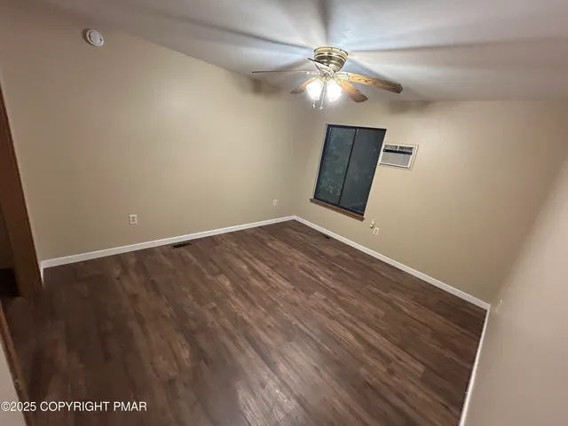 an empty room with wooden floor fan and window
