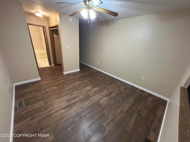 en empty room with wooden floor and fan