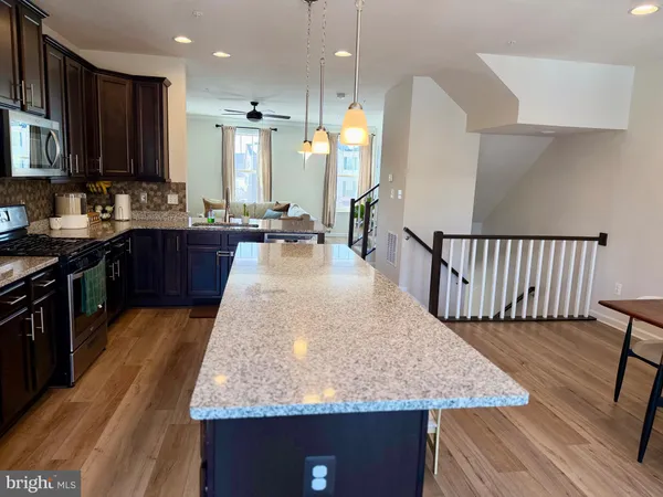 a large kitchen with kitchen island granite countertop wooden cabinets a stove a sink and a dining table