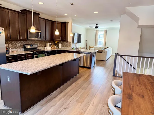 a kitchen with stainless steel appliances granite countertop a sink dishwasher a stove and a refrigerator with wooden floor