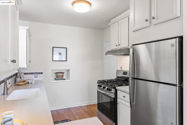 a kitchen with stainless steel appliances a refrigerator a stove a sink and white cabinets