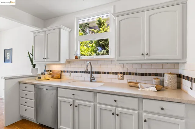 a kitchen with stainless steel appliances white cabinets and a window