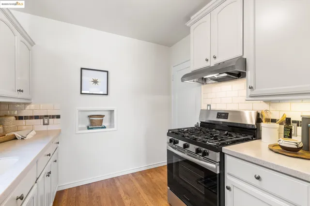 a kitchen with stainless steel appliances granite countertop white cabinets and a stove top oven