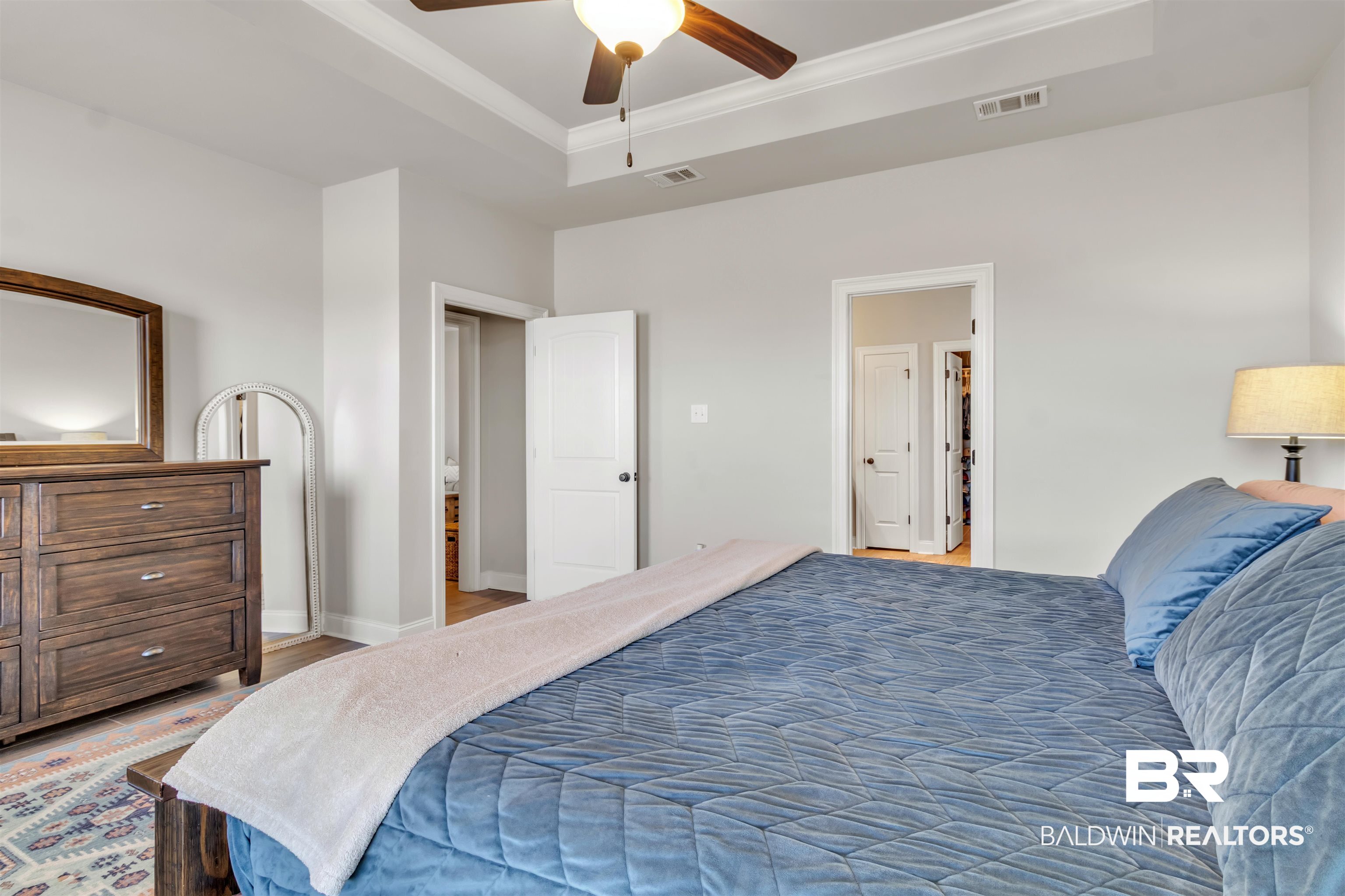 22531 Putter Lane Foley, AL 36535 - Photo 20 of 43 Bedroom featuring a ceiling fan, wood finished floors, ornamental molding, and a tray ceiling