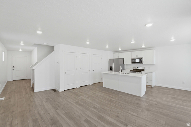 3788 South Galatia Road Magna, UT 84044 - Photo 6 of 24 Modern kitchen featuring white cabinetry, a central island with a sink, stainless steel appliances, and recessed lighting