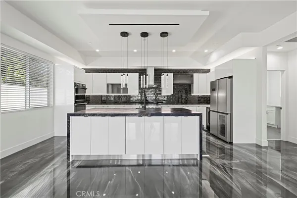 a large white kitchen with wooden floor and chairs