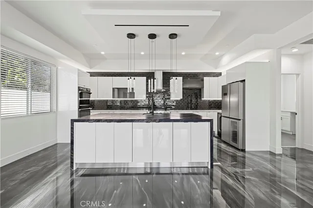 a large white kitchen with wooden floor and chairs