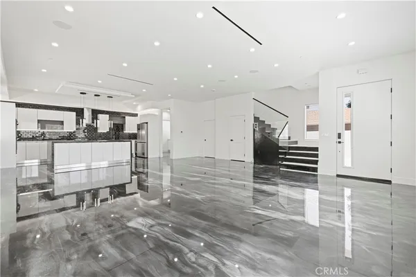 a large white kitchen with wooden floor and chairs