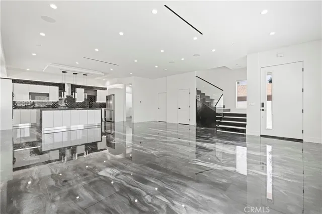 a large white kitchen with wooden floor and chairs