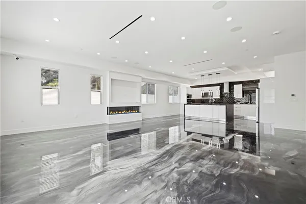a large white kitchen with granite countertop a stove top oven a sink a dining table and chairs with wooden floor