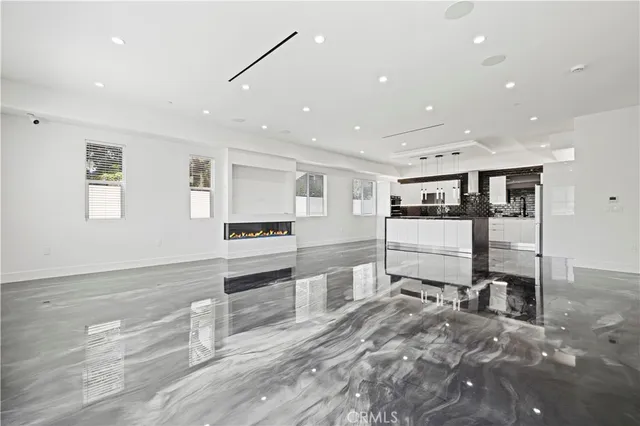 a large white kitchen with granite countertop a stove top oven a sink a dining table and chairs with wooden floor