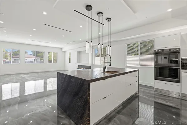 a kitchen with stainless steel appliances granite countertop a sink a refrigerator and a stove