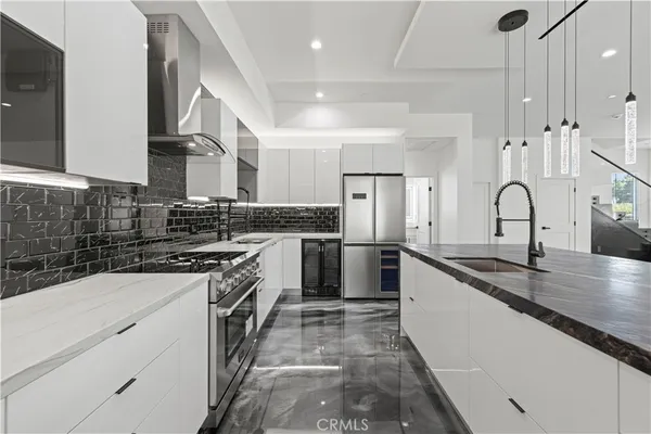 a kitchen with stainless steel appliances kitchen island granite countertop a refrigerator and a sink