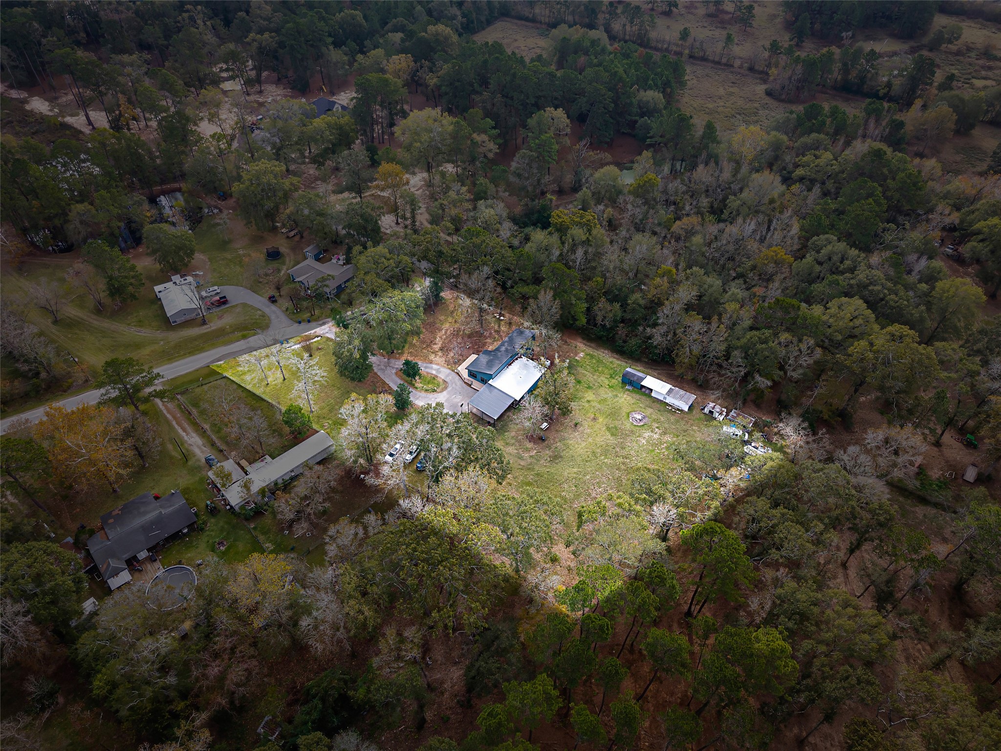 15080 Usher Lane Splendora, TX 77372 - Photo 10 of 44 This aerial photo showcases a spacious property surrounded by dense trees, offering privacy and natural beauty. The central home has a large yard, ideal for outdoor activities, with additional structures nearby. The area is secluded yet accessible, providing a perfect balance for serene living.