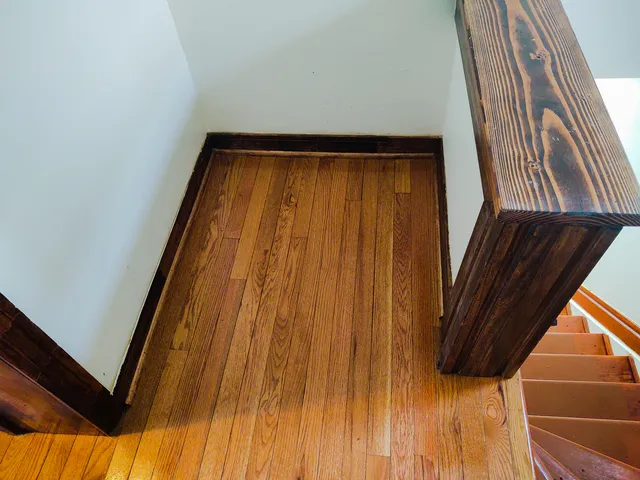 a view of an empty room with wooden floor and window