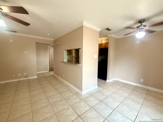a view of an empty room with window and chandelier fan