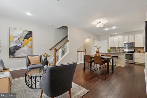 a living room with furniture kitchen view and a wooden floor