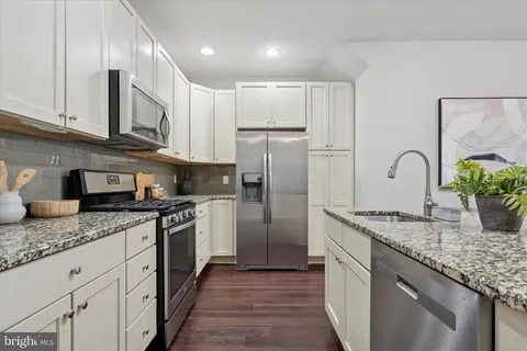 a kitchen with granite countertop stainless steel appliances a sink stove top oven and refrigerator