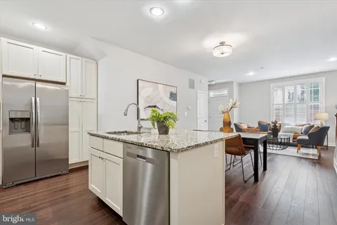 a kitchen with stainless steel appliances granite countertop a table chairs and a refrigerator